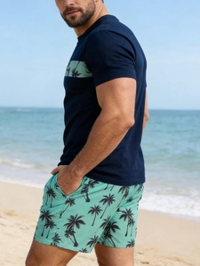 Detail von Herren Marine T-Shirt und mintgrünen Palmen-Shorts an einem sonnigen Strand