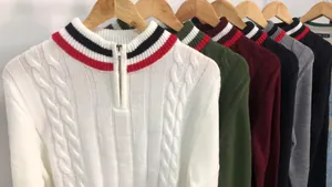 Close-up of cable-knit men's sweaters with quarter-zip collar and color-block striped details