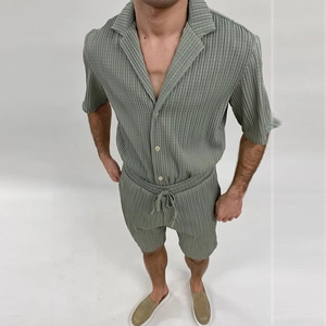 Close-up detail of light green plisse fabric texture on men's short sleeve shirt and shorts set