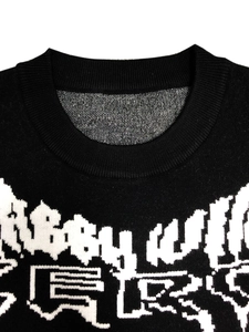 Close-up of ribbed crew neck and white geometric pattern on black knit sweater