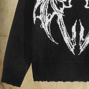 Detail of black knit sweater with distressed hem and white gothic graphic pattern