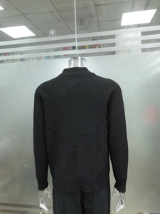 Detail of black knit cardigan showing checkered texture and ribbed cuffs on back