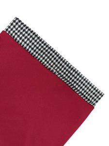 Detail of burgundy polo shirt fabric showing knit texture and houndstooth pattern trim