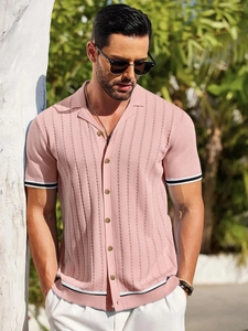 Detailed view of pink knitted polo shirt with black and white striped cuffs and amber buttons