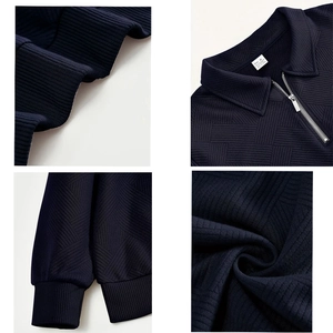 Detail of navy blue half-zip sweatshirt showing 3D geometric jacquard texture and ribbed cuffs