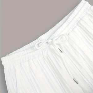 Gros plan d'un pantalon plissé blanc avec taille élastique et embouts de cordon en métal