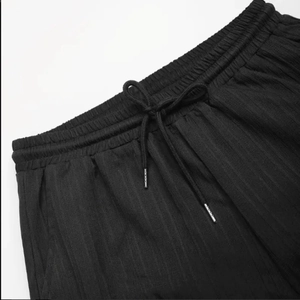 Détails du pantalon noir à rayures verticales montrant la taille élastique avec cordons métalliques
