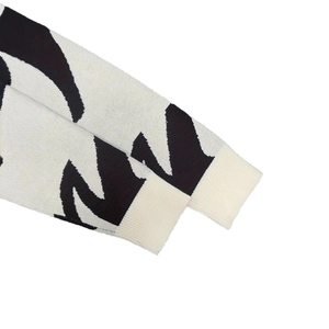 Close-up of knit sweater cuff with black and white jacquard pattern and ribbed detailing
