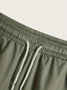 Detail of army green beach shorts featuring elastic waistband and white drawstrings