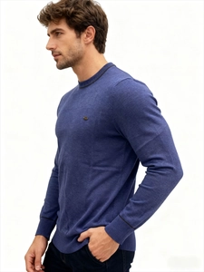 Detail of blue knitted sweater showing black striped trim on neckline and metal logo
