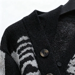 Dettaglio del cardigan in maglia jacquard con motivo a ossa bianche e bottoni scuri fini