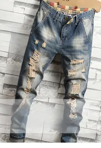 Detail view of distressed light blue denim jeans with ripped holes and vintage washed finish