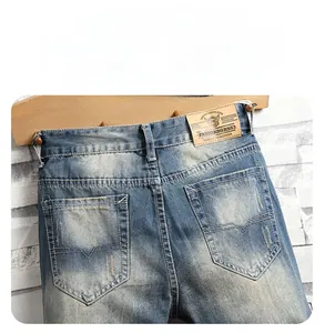 Detail of vintage washed blue denim jeans featuring geometric embroidery on the back pocket