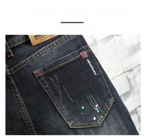 Detail einer dunkelgrauen Herrenjeans mit Farbspritzern und distressed Gesäßtasche