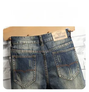 Détail du jean bleu délavé avec couture en V sur la poche arrière et patch en cuir à la taille