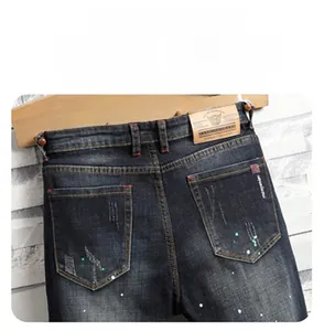 Detailansicht der Slim-Fit-Jeans mit Distressed-Farbspritzern und Leder-Taillenaufnäher