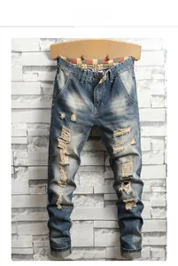 Close-up of vintage washed blue denim jeans featuring heavy distressed rips and frayed details