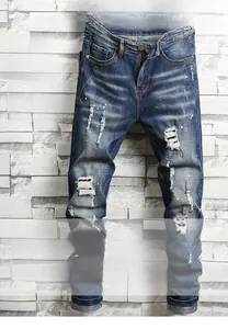 Detail of blue distressed slim jeans featuring paint splatters and ripped knee textures