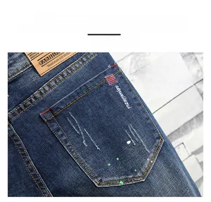 Detail of blue denim jeans featuring back pocket stitching, leather patch, and paint splatters