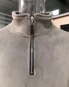 Détail de sweat en polaire à col montant avec demi-fermeture éclair et tirette en cuir