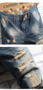 Close-up of distressed denim jeans with vintage wash and red plaid waist lining