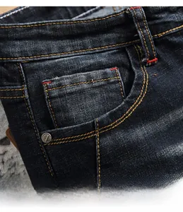Detailaufnahme der Vordertasche einer blauen Jeans mit verstärkten Nähten und Metallniete