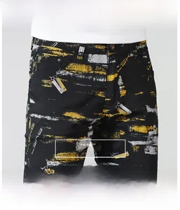 Detail of slim-fit black jeans featuring yellow and white paint splatter print with LSK letters