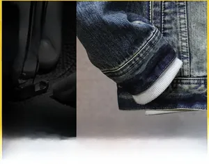 Detail of blue washed denim jacket sleeve with white knitted ribbed cuffs and firm stitching