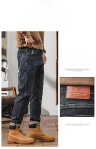 Detail view of leather waist patch and slim tapered fit design on men's dark blue jeans