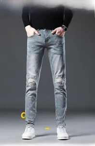 Detailed macro of light blue slim fit jeans featuring distressed knees and paint splatter