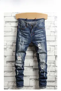 Detail of distressed dark blue slim fit jeans with vintage wash and paint splatter