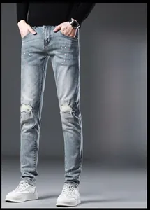 Detail of light blue slim fit denim jeans with knee holes and colorful ink splashes