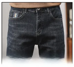 Detail of dark blue men's stretch jeans showing washed whiskers and brand logo on pocket