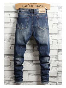 Detail of dark blue slim jeans featuring paint splatter effect and distressed denim textures