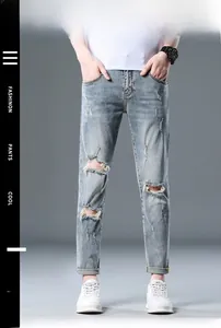 Detailed close-up of distressed ripped details on slim fit light blue men's denim jeans