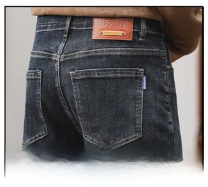Detailed close-up of dark blue jeans featuring back pocket with leather brand patch