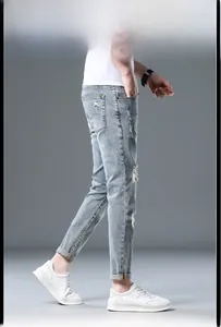 Close-up of slim-fit men's light blue distressed jeans with ripped knee and tapered hem detail