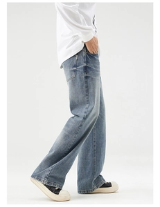 Side view of men's loose straight-leg jeans in washed mid-blue with side pocket detail