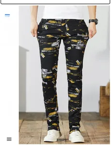 Detail view of men's slim fit black denim pants with yellow graffiti paint print