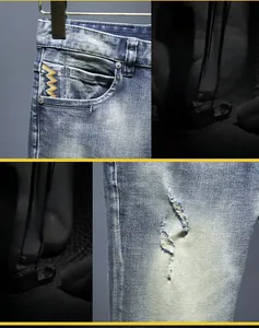 Dettaglio di pantaloncini in denim blu lavato con ricami decorativi e strappi in rilievo