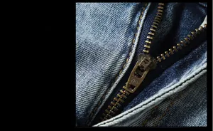 Detailed macro view of the YKK vintage metal zipper on blue washed denim jeans