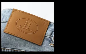 Detailed close-up of embossed leather waist label and faded denim texture on blue jeans