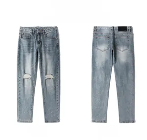 Front and back view of men's distressed light blue denim jeans with paint splatter details
