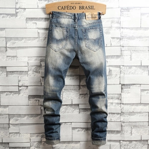 Men's vintage washed blue distressed denim jeans back view with leather brand patch