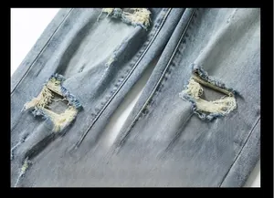Detailed close-up of light blue washed denim fabric with distressed ripped textures