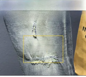 Dettaglio ravvicinato del tessuto denim lavato blu con strappi e cuciture colorate