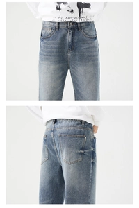 Detail of blue wash denim jeans showing belt loops and pocket stitching in studio view