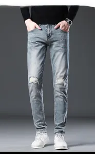 Detail shot of men's slim fit light blue jeans with distressed holes and colorful spray spots