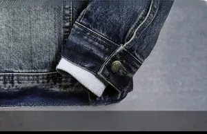 Detail of denim jacket cuff with vintage metal button and white knit inner lining