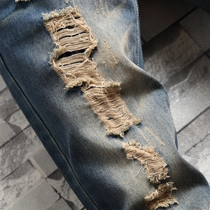 Retro distressed blue jeans for men with heavy washing and stylish ripped knee details